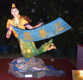 花灯“飞天”——身姿轻盈曼妙的仙女，以天衣彩带飞扬，手上拿着“真、善、忍”旗子，脚踏彩云来到人间，告诉世人修炼法轮大法的美好。