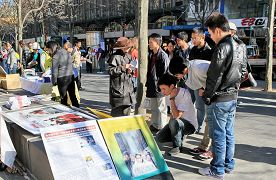 路人驻足观看中共迫害民众展板