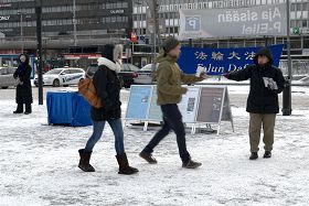 '行走匆忙的路人从法轮功学员手中接过真相资料'