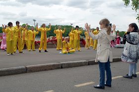 大法弟子祥和的炼功场面，吸引着这二位小朋友认真学炼。