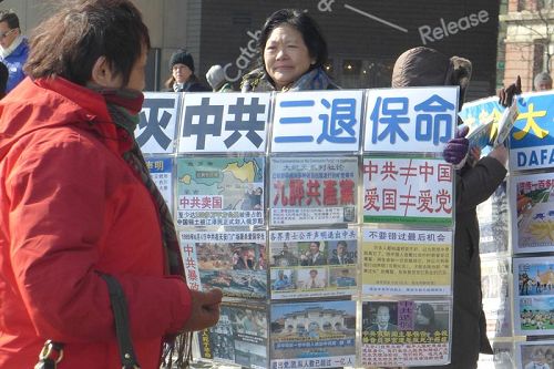 纽约自由女神像附近，法轮功学员向游客展示真相展板。