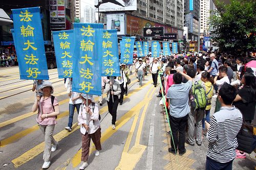 图9-14：法轮功阵容庞大整齐的游行队伍吸引中西游客及港民驻足观看，纷纷举起相机、手机拍照。