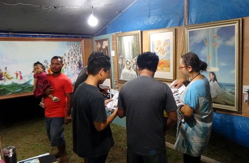 图1-6：“真善忍国际美展”来到塞班岛火树节，每天都有大批的民众驻足聆听法轮功学员的讲解