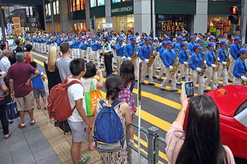 图4：民众喜见法轮功游行队伍，纷纷拿起手机、相机拍照留念。