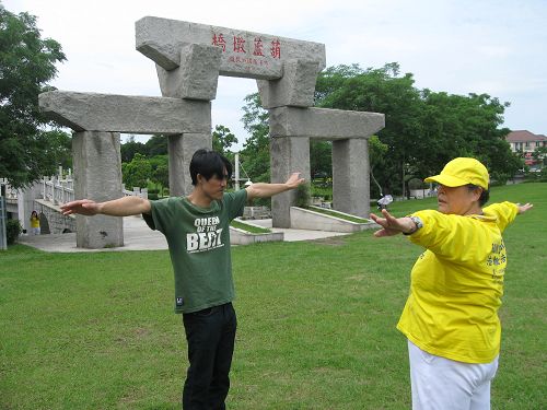 图5：正好经过公园的杨先生看到现场有这么多法轮功学员，很有兴趣的走进了解，经过学员介绍后，他兴起学炼的想法，于是询问起炼功点，并且开始跟学员学炼起来。