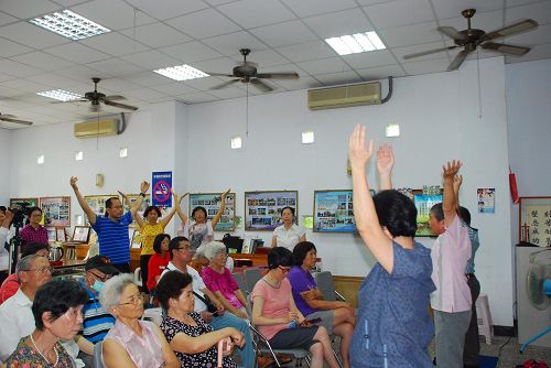 观看着法轮功学员的功法演示，有的民众当场跟着学员学炼动作。