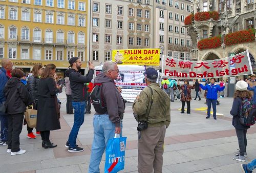 '图1：法轮功学员在玛琳广场展示功法及揭露中共活摘器官的横幅吸引了民众观看。'