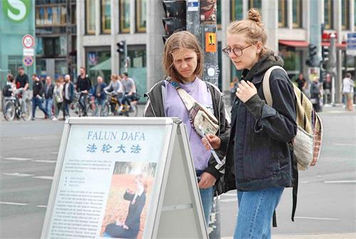 '图5：波兰女孩在展板前仔细阅读，感到中共对法轮功学员的迫害触目惊心。'