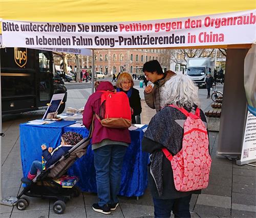 '图6：推着婴儿车的易得黑姆·乌哈姆女士在反对中共活摘器官的请愿书上签名'