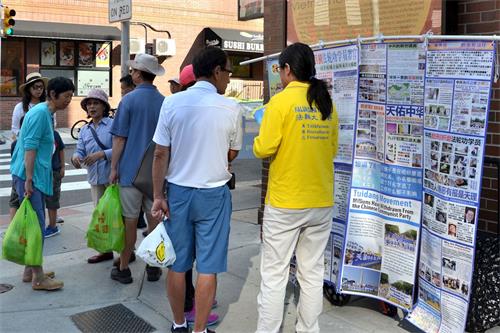 '图2：民众在观看法轮功真相展板，了解真相。'