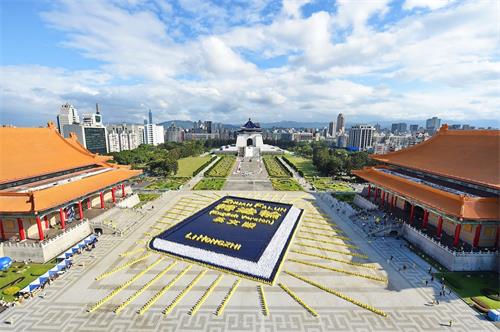 '图1：二零一八年十一月二十四日，约五千四百名法轮功学员于台北自由广场排出巨幅的英译本《转法轮》：深蓝色的书皮、金黄色的书名与作者名、白色的书页，并绽放四十二道金黄色的光芒，场面壮观殊胜。'