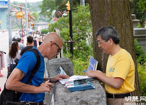 '图3：游客在尼亚加拉大瀑布炼功点了解法轮功真相并签名支持反迫害。'